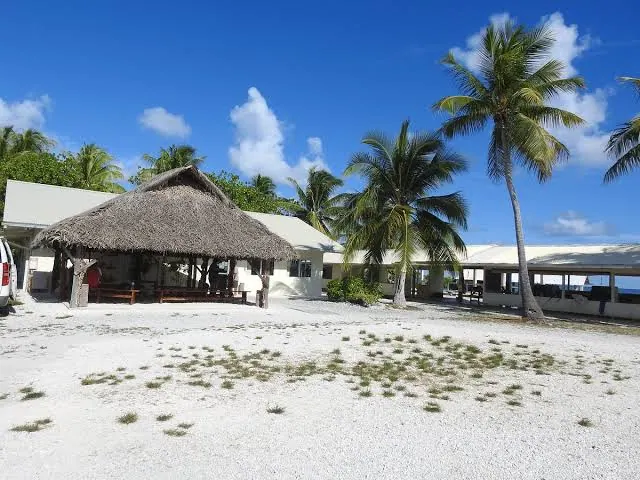 Ferme perlière au bord du lagon, fare au toit de pandanus sur le sable blanc